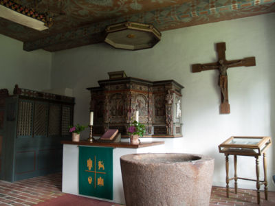 Innenaufnahme der Halligkirche auf Hallig Oland, zu sehen sind Taufbecken und Altar